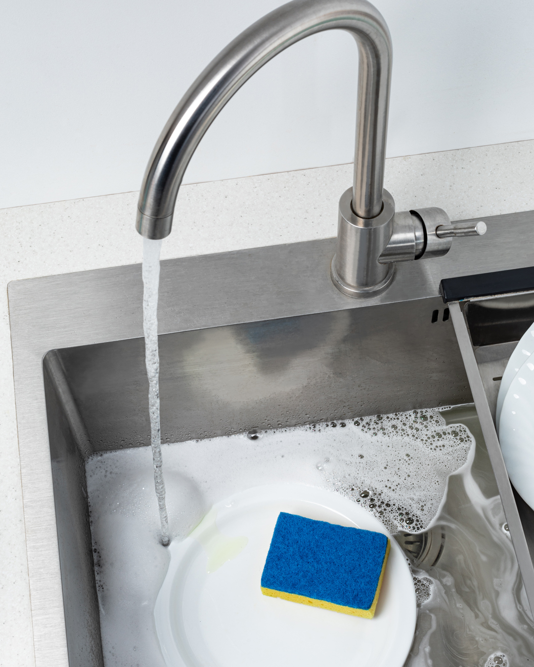 doing dishes in kitchen sink with a water filtration can help save money
